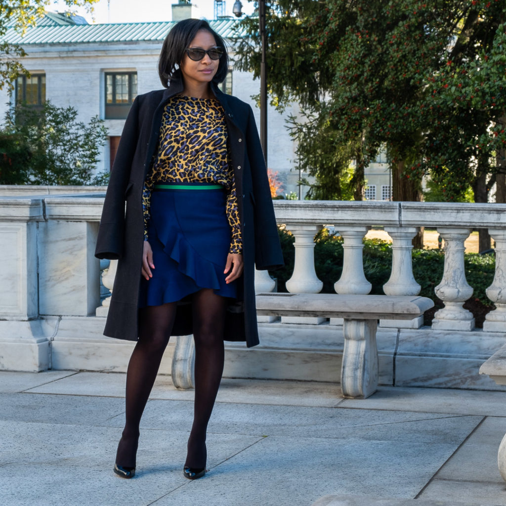 Full image of blue and yellow leopard print top and blue ruffle skirt with green waistband with J Crew coat