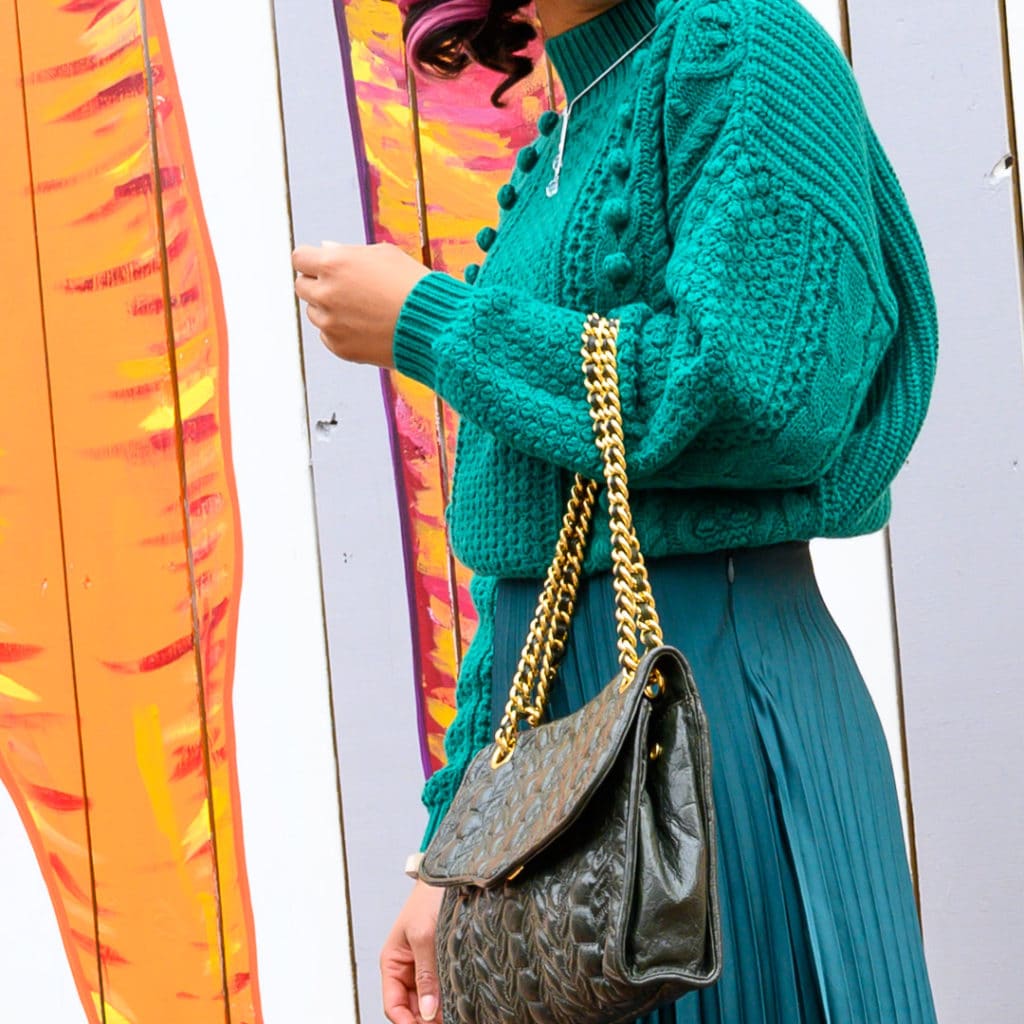 close up of rebecca minkoff purse and emerald green sweater